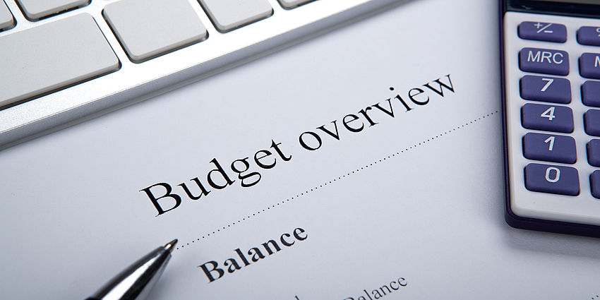 budget report showing tables of numbers, next to a calculator and a pen