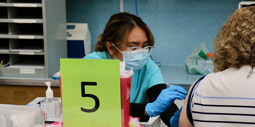 public health worker administers vaccine  at clinic.