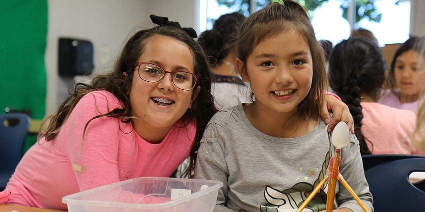 two girls smiling with their project