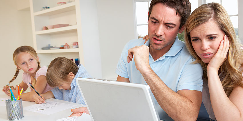parents looking puzzled at laptop as students work at table