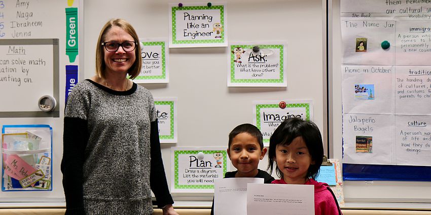 teacher at whiteboard with two students