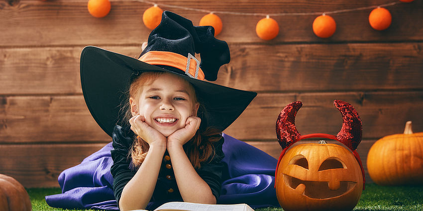 little girl in costume with a pumpkin
