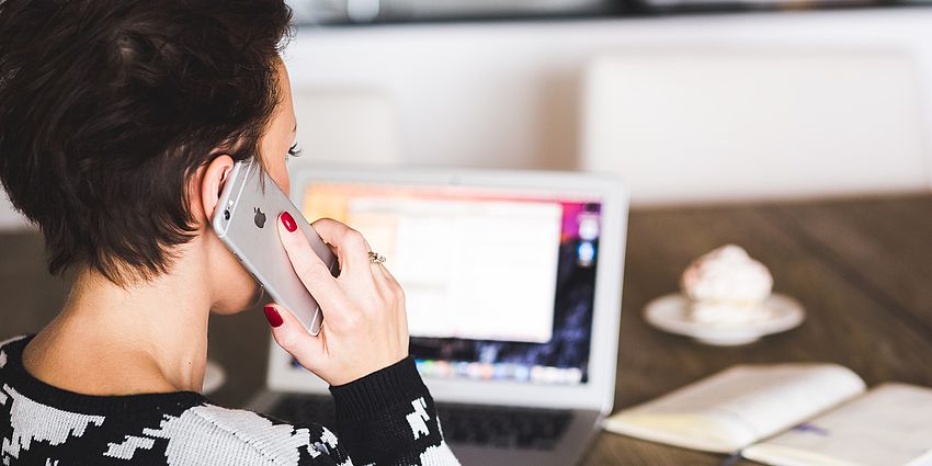 woman talking on phone while at the computer