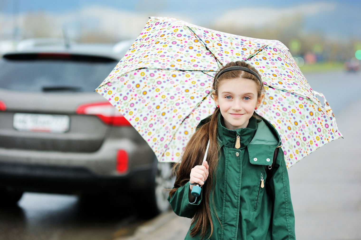 smiling girl holding umbrella as car drives away